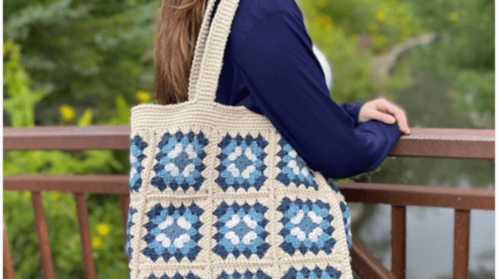 granny square tote bag on a woman's shoulder. Bag is white with blue granny squares