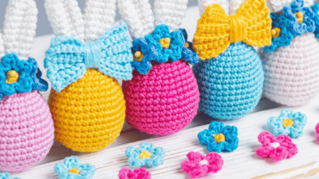 Crochet easter bunny eggs in bright colors. Some have bow ties and some flowers.