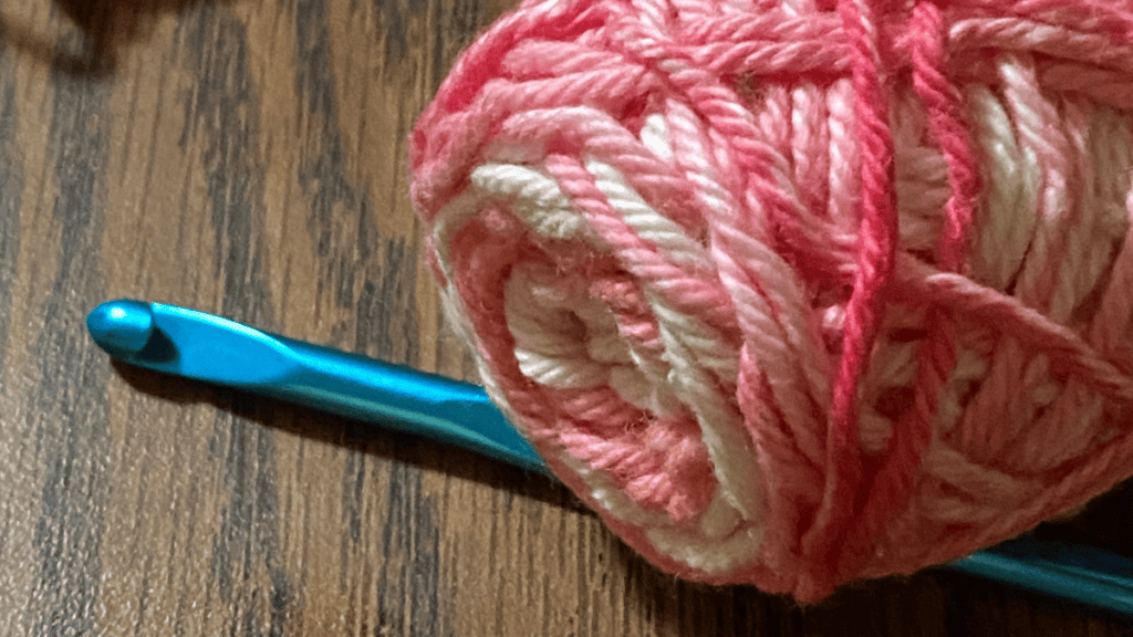 pink and white yarn with crochet hook