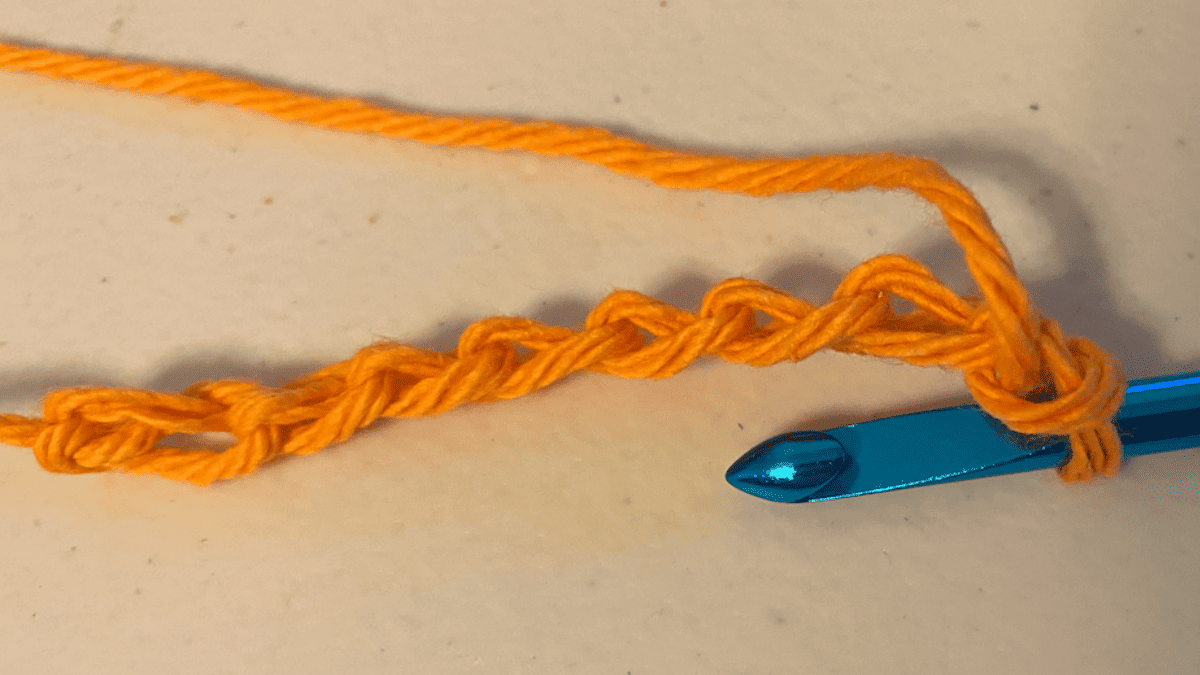 foundation row for the tunisian crochet purl stitch in orange yarn