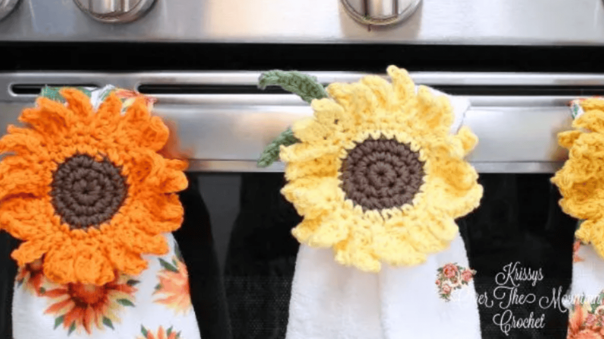 3 sunflowers dishtowel topper hanging from a stove