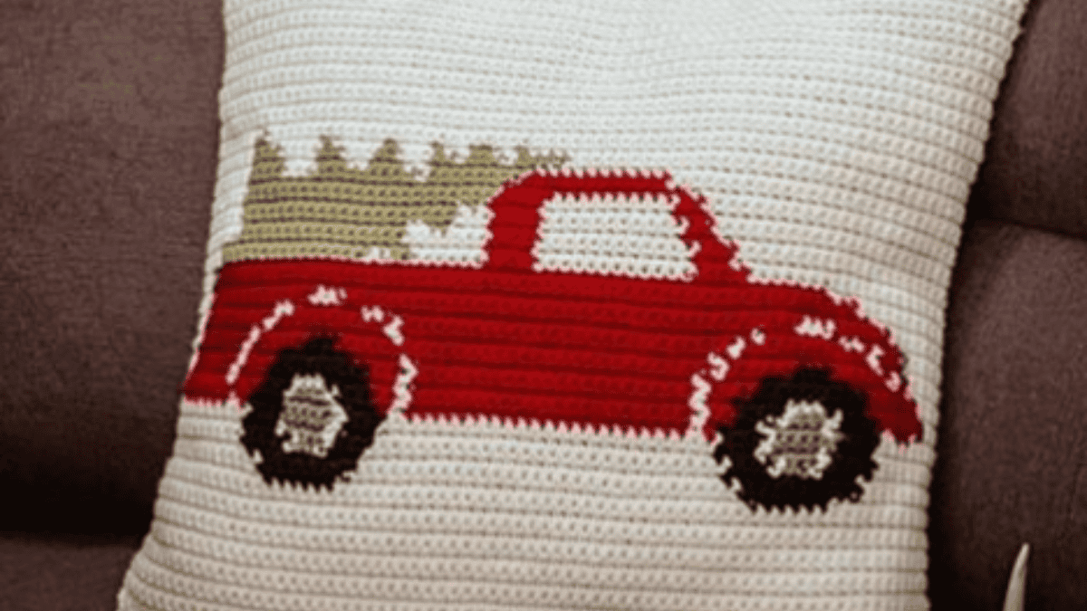 cream pillow with red truck carrying tree