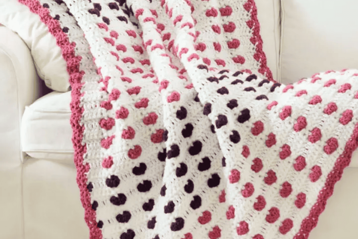 White crochet blanket with different colored hearts